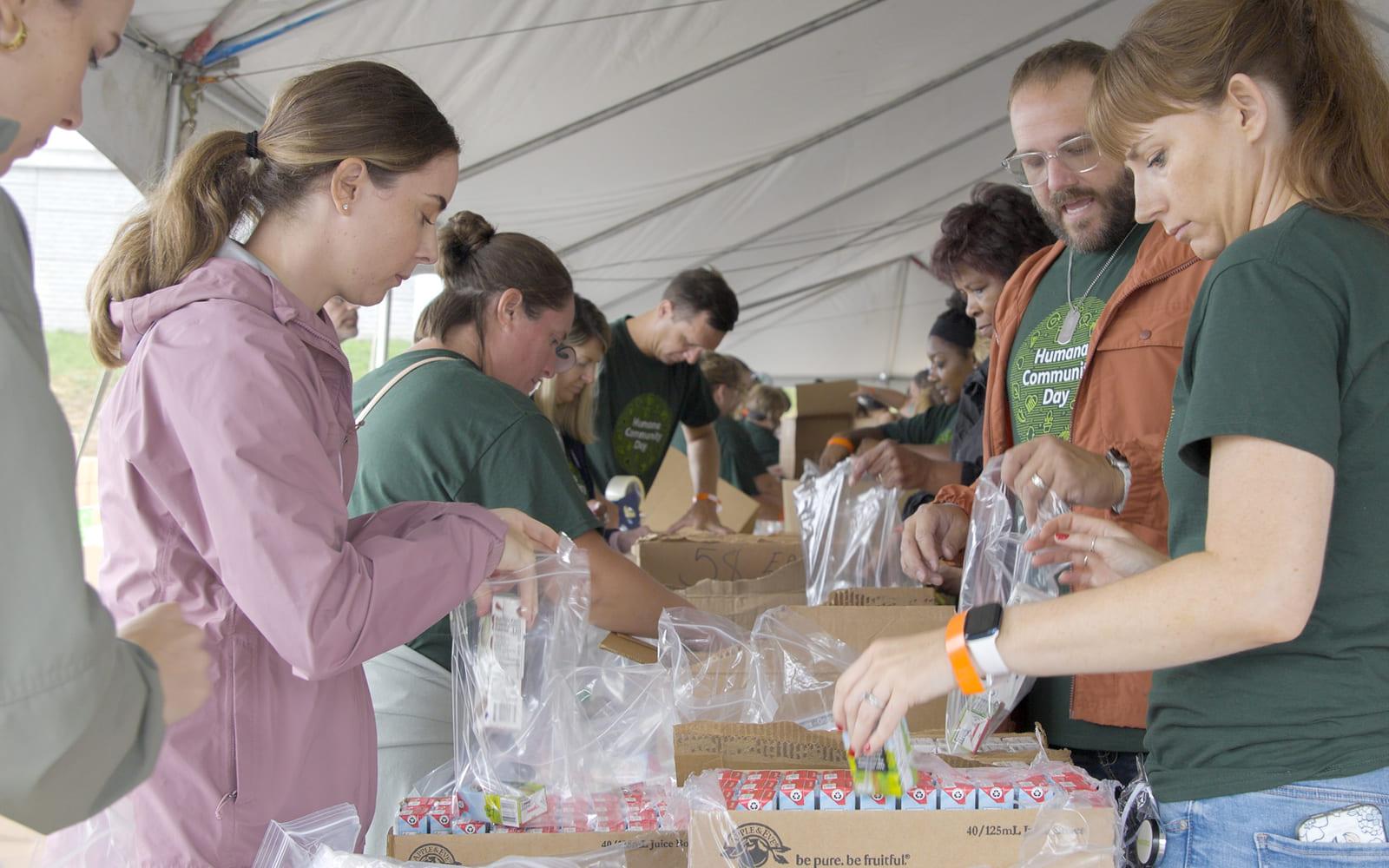 Humana Community Day volunteers filling kit bags under a tent