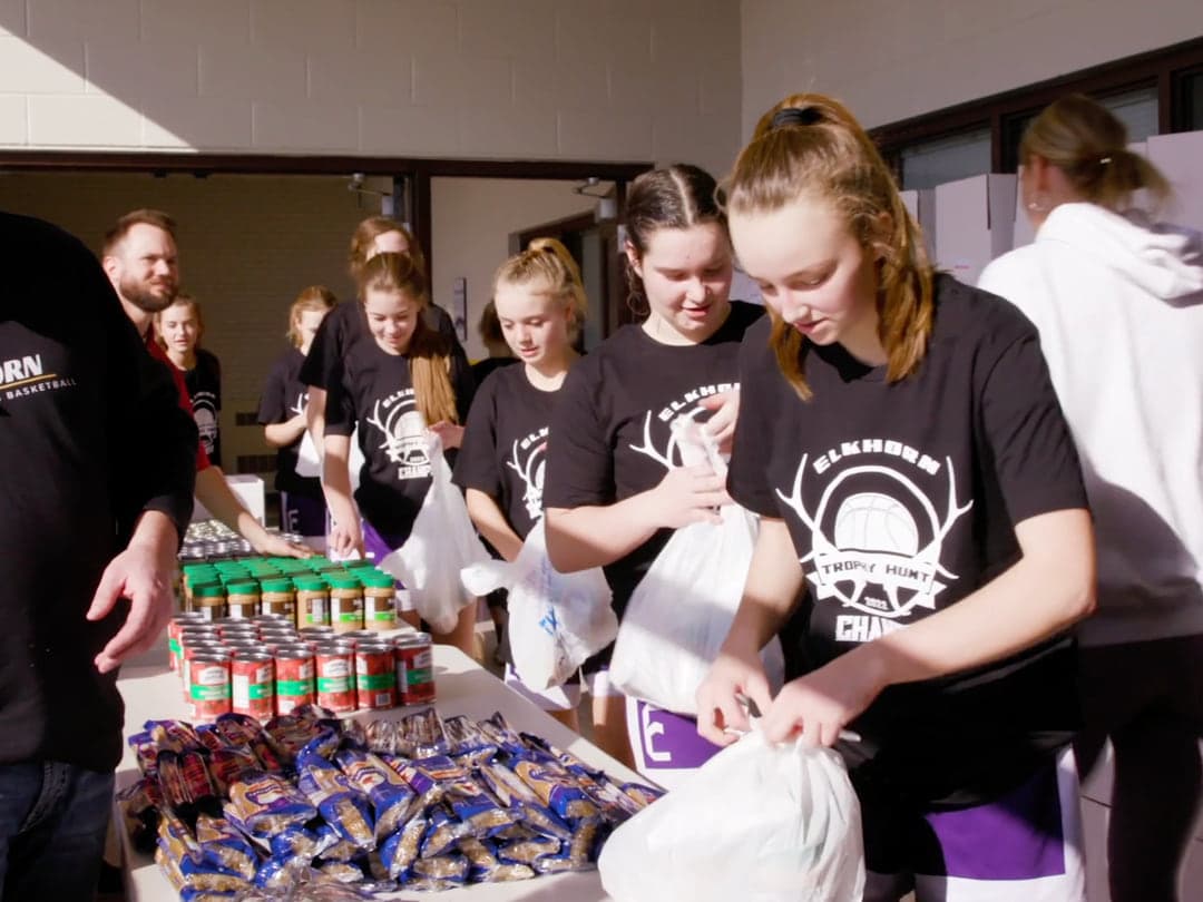 Student athletes bagging groceries from a table of canned goods