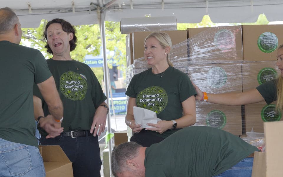 Humana volunteers beside shrink-wrapped pallets of finished kits