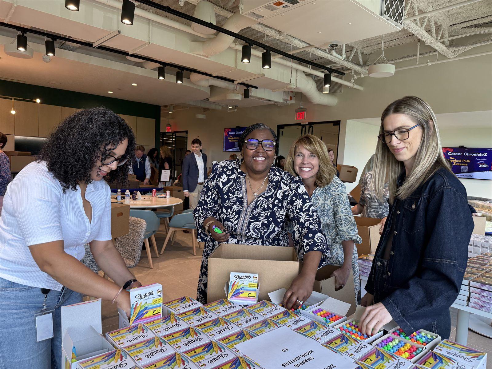 Four Zelis volunteers packing boxes of highlighters into teacher appreciation kits